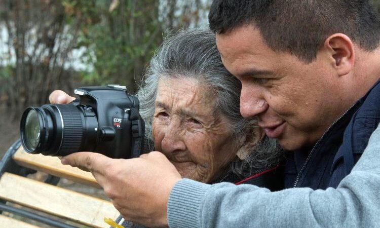 Héctor Fabio Zamora enseñando la fotografía a una mujer mayor
