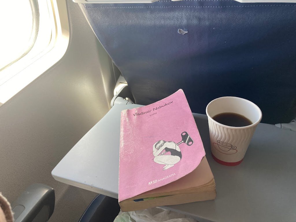 Libro de Lolita y un café en la mesa de un avión