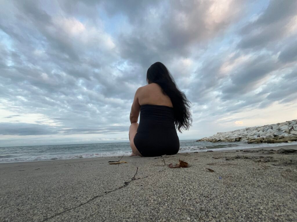 Diana sentada sola en la playa de Santa Marta al amanecer