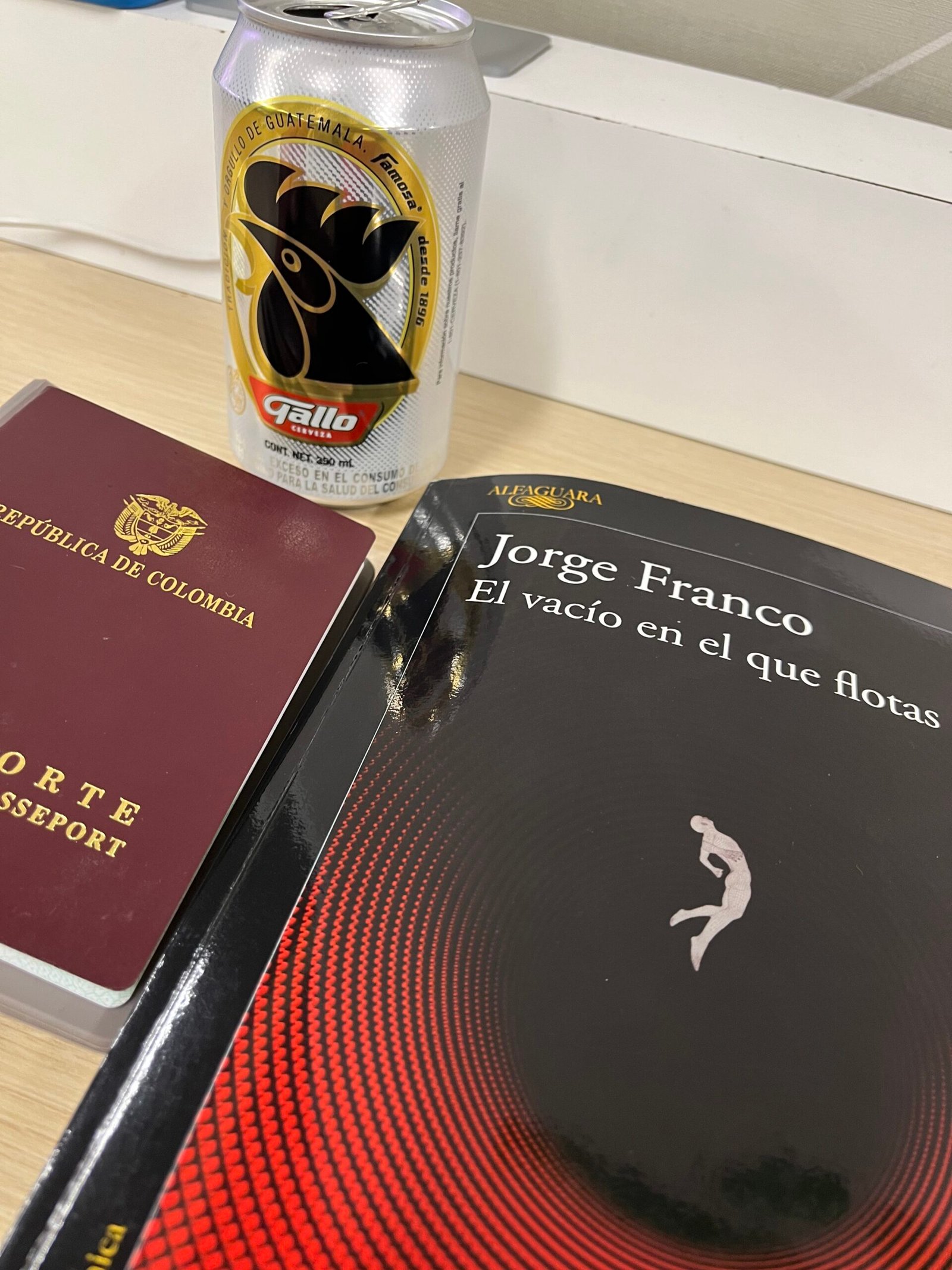 Portada del libro El vacío en el que flotas del escritor Jorge Franco. Pasaporte colombiano y la cerveza Gallo, la típica de Guatemala