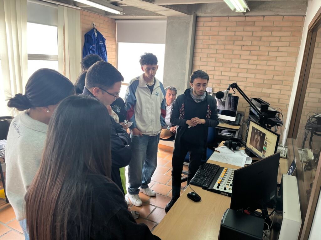 Clase de Periodismo en la radio. Daniel explicando manejo de la consola. Estudiantes atentos a la explicación.