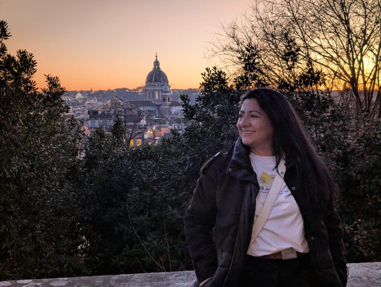 El atardecer de Roma.
Mirador en Villa Borghese de Roma. Foto de Diana Socha en el borde de un muro, detrás los árboles y al fondo se ve la ciudad. Tomada por Jaime Cortés