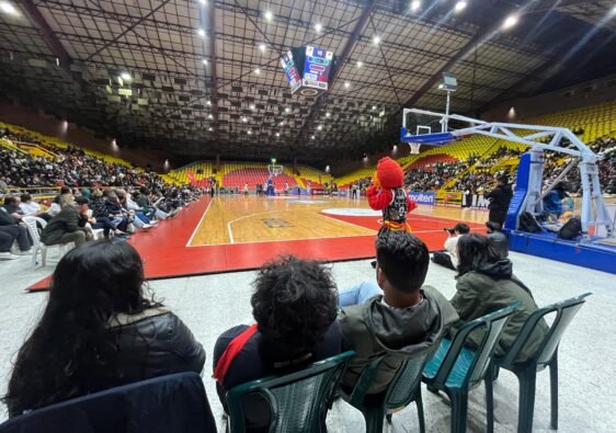 Cuatro sillas instaladas frente a la cancha. Cuatro personas y la mascota de Piratas viendo de cerca el partido de baloncesto