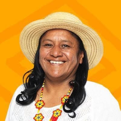 Aida Quilcué sonrié frente a la cámara, tiene un sombrero y un collar