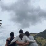 Tres amigas abrazadas mirando el paisaje del Valle del Cocora. Montañas, cielo nublado y las palmeras gigantes