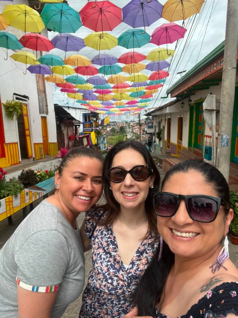 Carmen, Maritza y Diana en una calle de Salento, donde hay sobrillas de colores colgadas