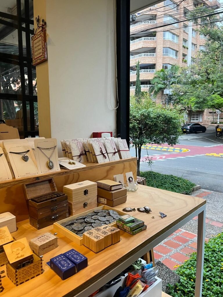 collares, relicarios, separadores de libros, cajas musicales y sellos sobre una mesa, al fondo el barrio laureles de Medellín
