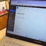 al fondo unos libros y se ve la pantalla del computador a punto de comenzar un texto