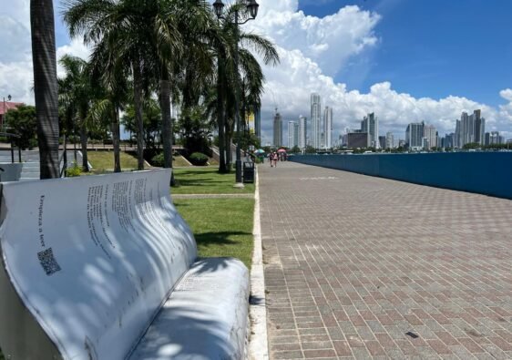 Se ve la ciudad de panamá unas palmeras haciéndole sombra a una silla en forma de libro