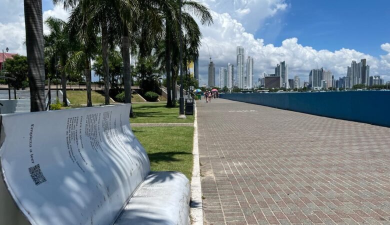 Se ve la ciudad de panamá unas palmeras haciéndole sombra a una silla en forma de libro