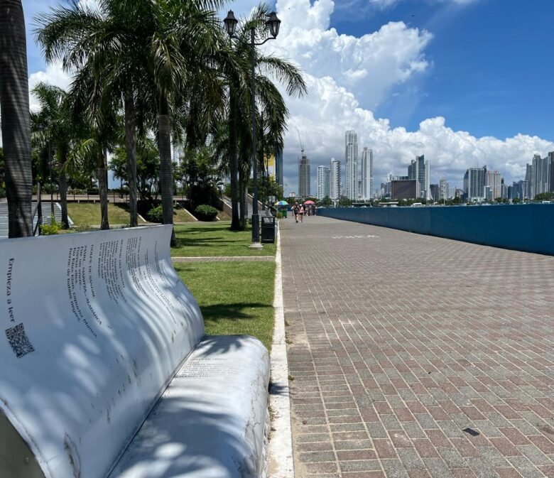 Se ve la ciudad de panamá unas palmeras haciéndole sombra a una silla en forma de libro